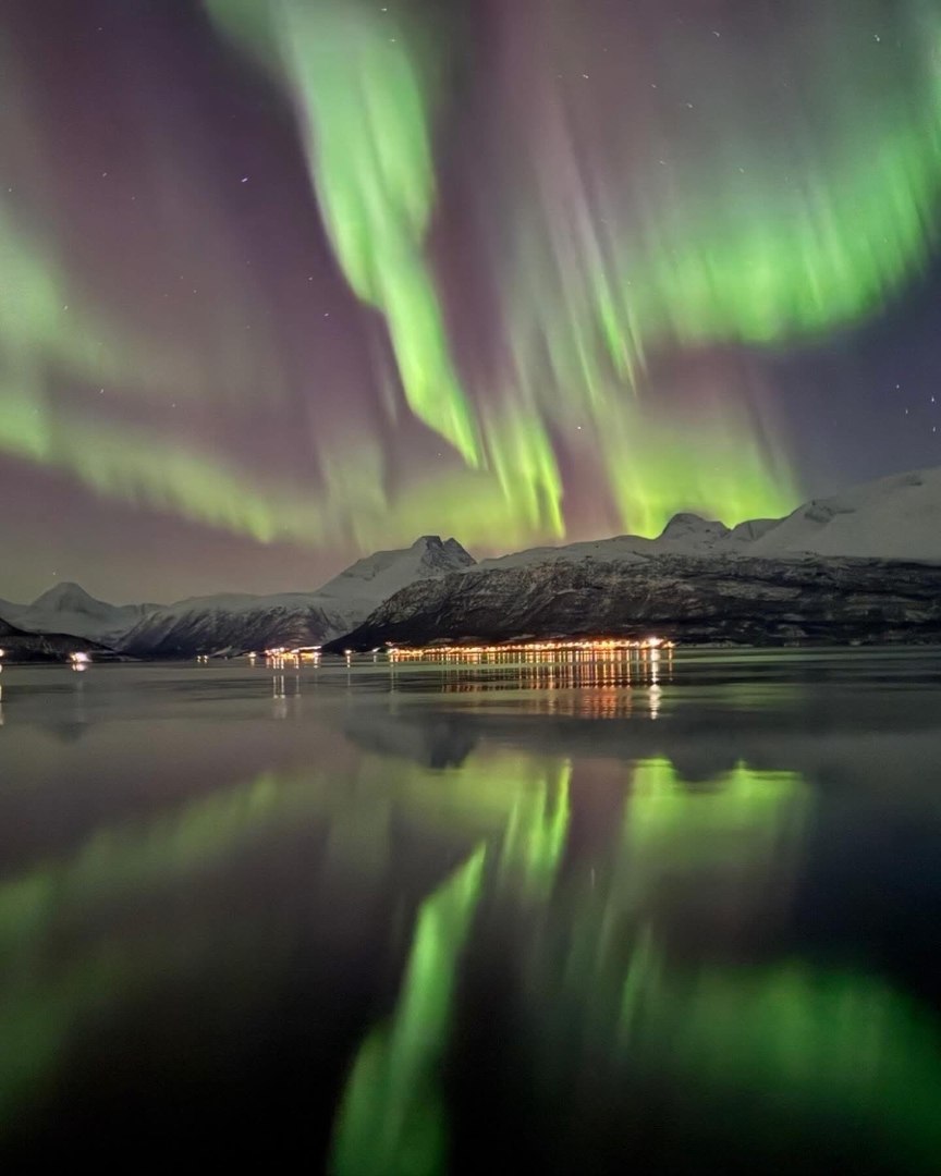 Nordlys over fjorden og fjellene